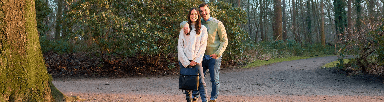 Paar beim Waldspaziergang mit schwarzem Rucksack, Frau und Mann in lässiger Outdoor-Kleidung auf Waldweg, Natur-Lifestyle